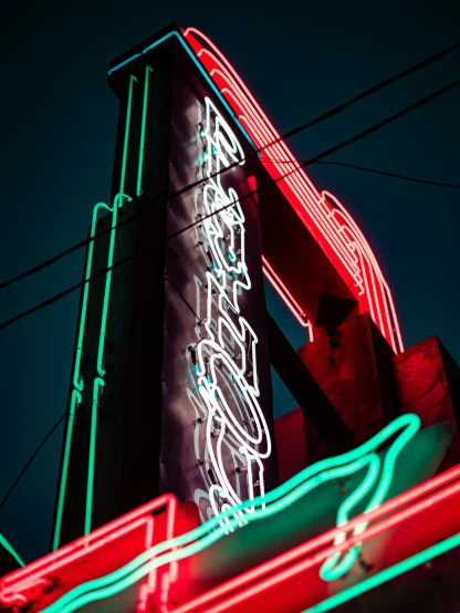a neon sign sitting under a building with electrical wires
