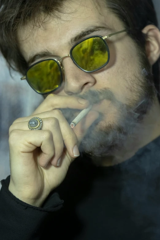 a man with glasses smoking a cigarette and looking at soing