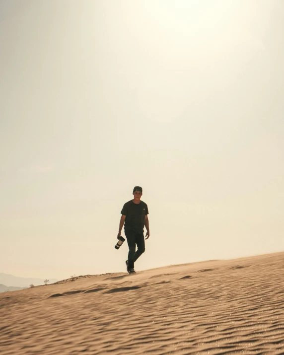 there is a man walking across a dune