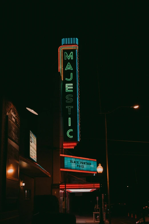 a lighted theater sign sitting next to a dark night sky