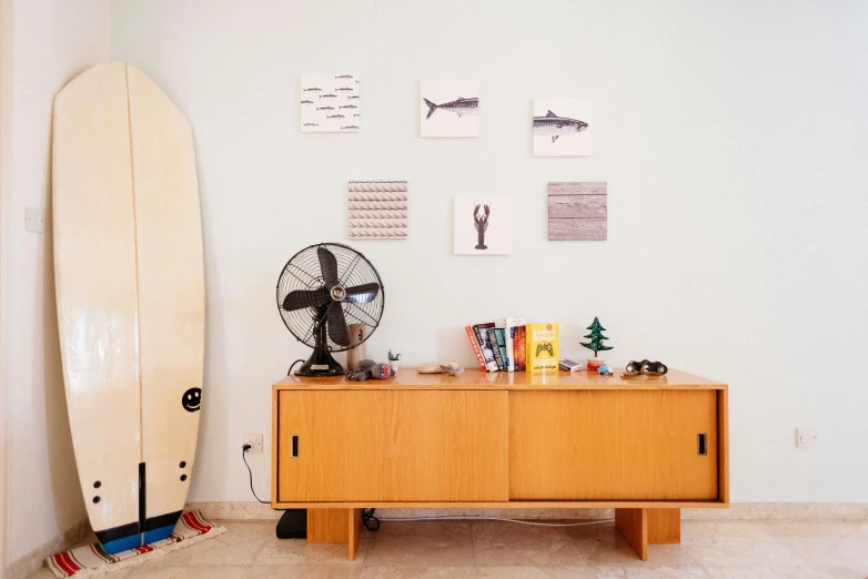 a white surfboard in the background with wood cabinet below it and pos on the wall above