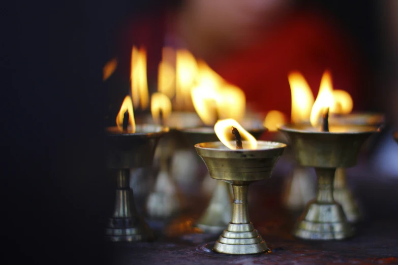 many candles on a table in gold colored containers