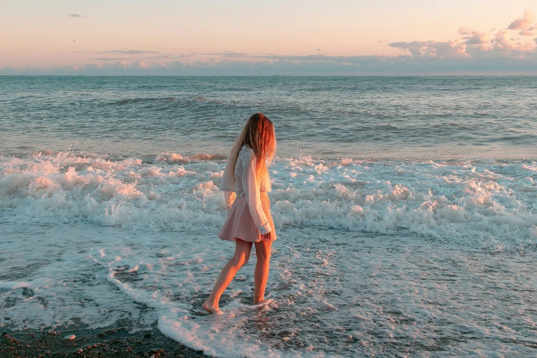 a girl in the water on the beach looking at soing