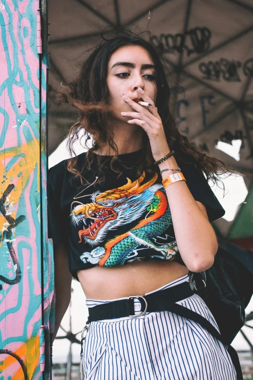 a young woman standing next to a colorful wall smoking