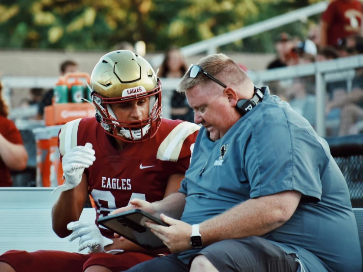 two players sit on the bench using their tablets