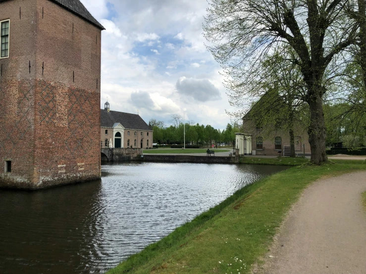 a river near a large brick building with a tall tower