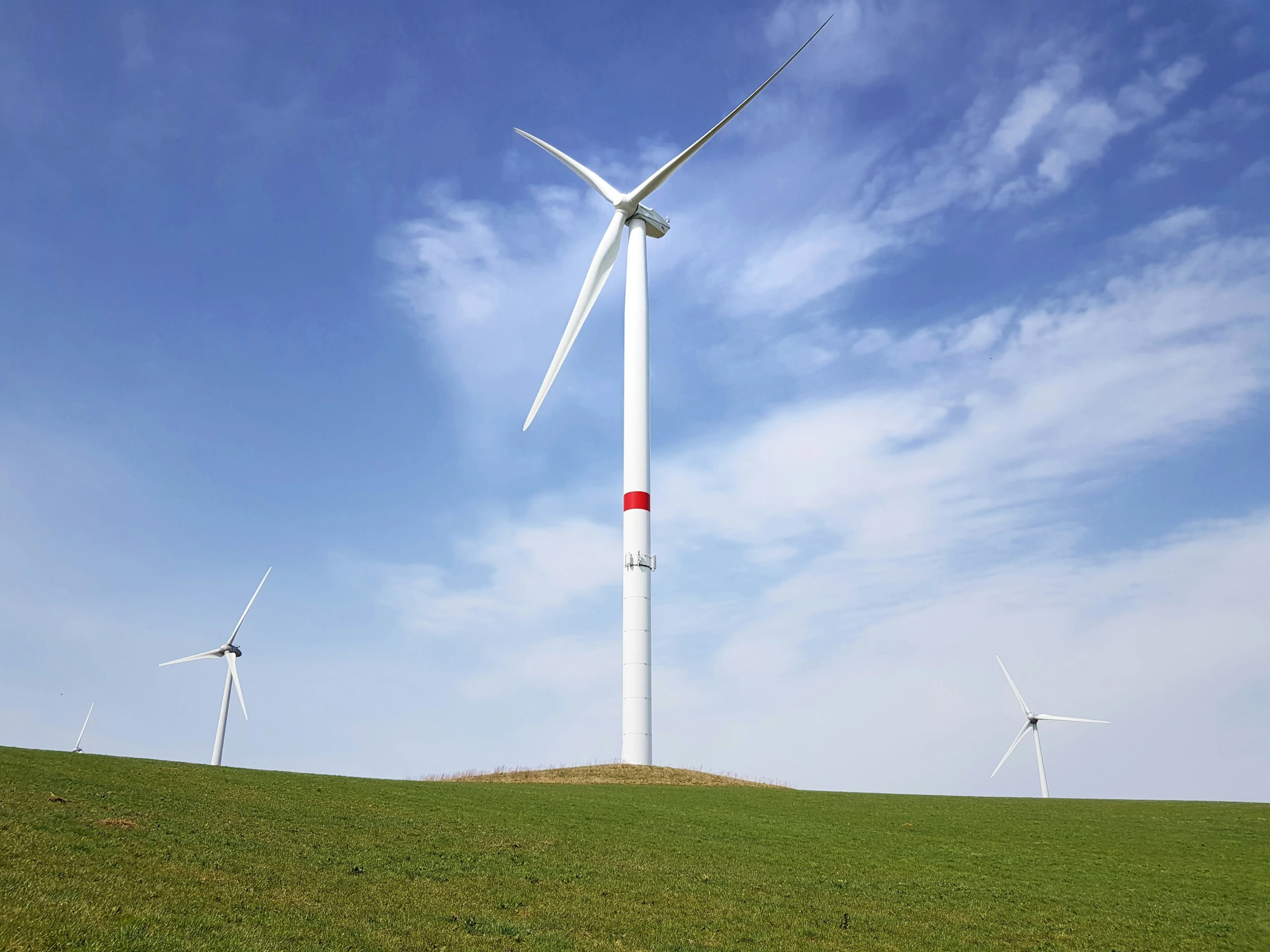 wind turbine on top of a hill with blue sky