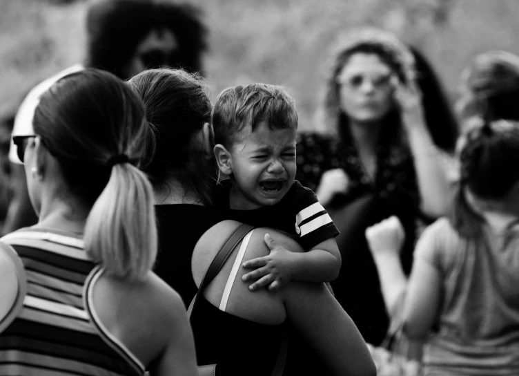 a woman holds the hand of a child that is crying