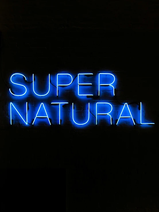 the neon word super natural is displayed against a dark background