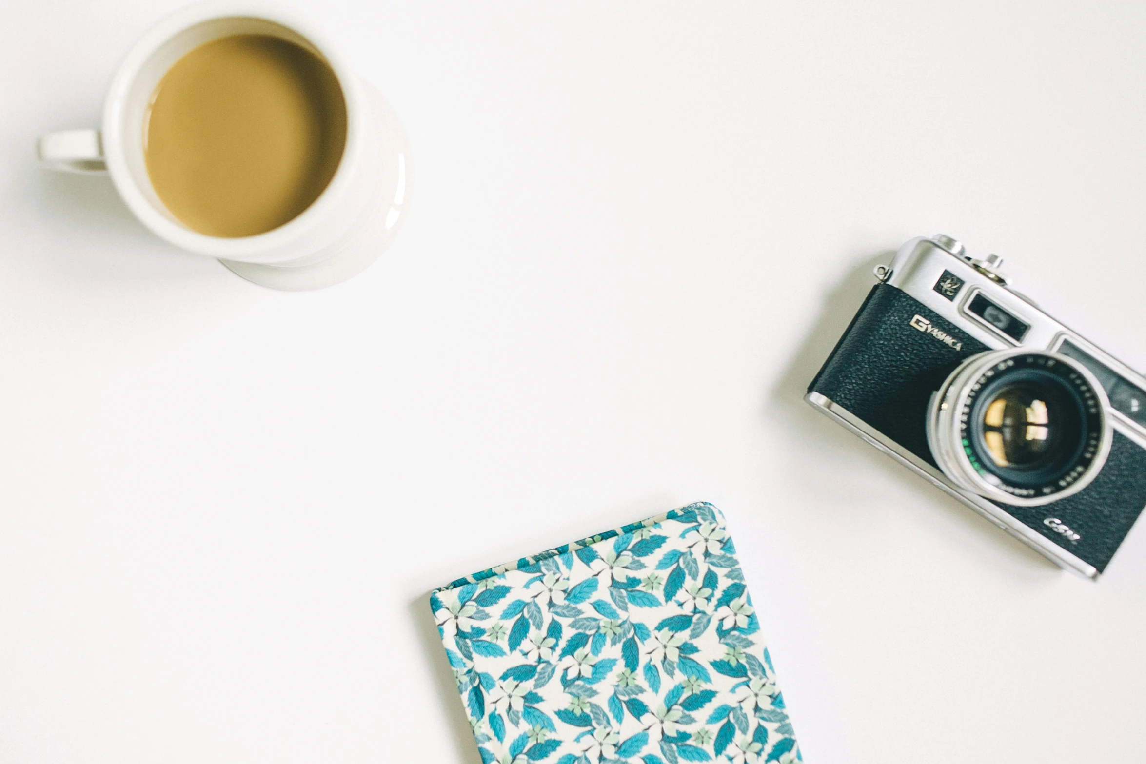 a cup of coffee, camera and card on a table