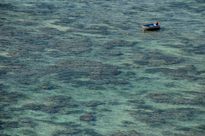 small boat traveling through clear blue water with no hull