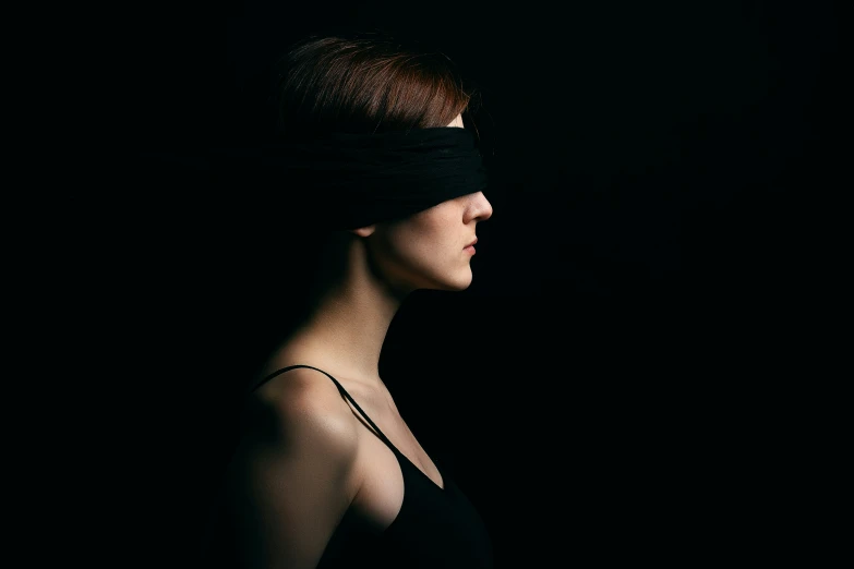 a young woman in blindfolds stares at the camera