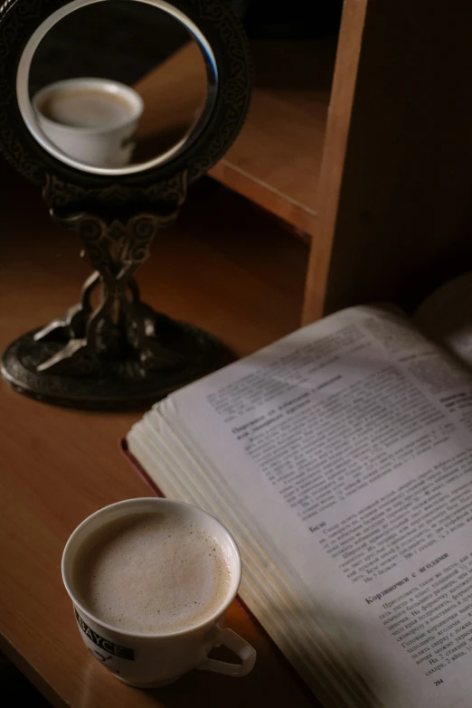 a cup of coffee next to an open book