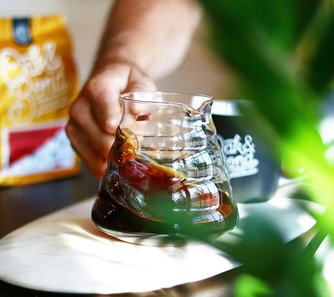 someone putting a liquid in a glass on top of the table