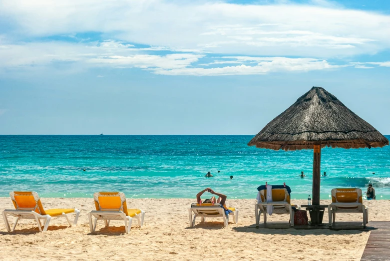 chairs under a straw umbrella on the beach