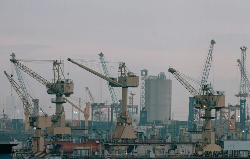 several cranes are on some docks near an industrial area