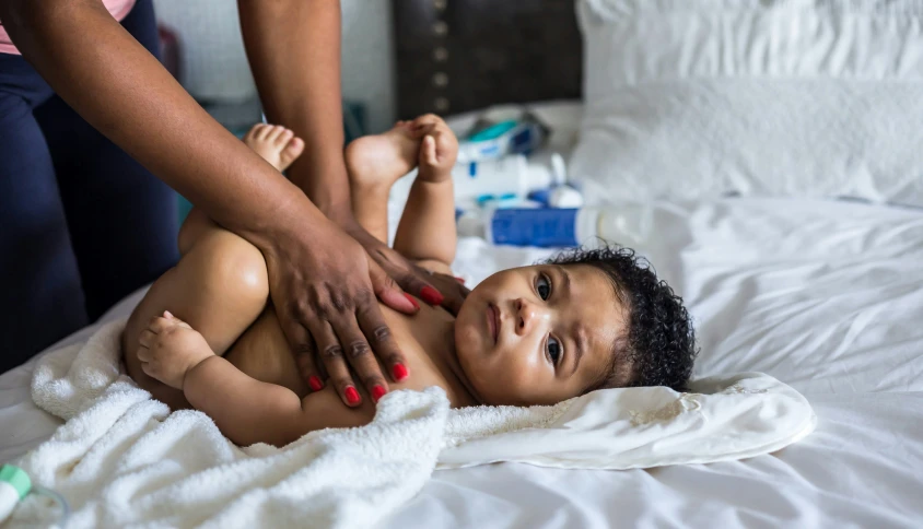 an adult reaches into the air to hold the baby's feet