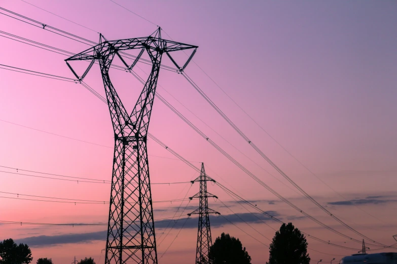 the electric towers are in a field during the setting sun