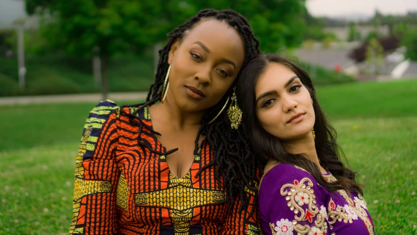 two beautiful women are sitting outside in a field