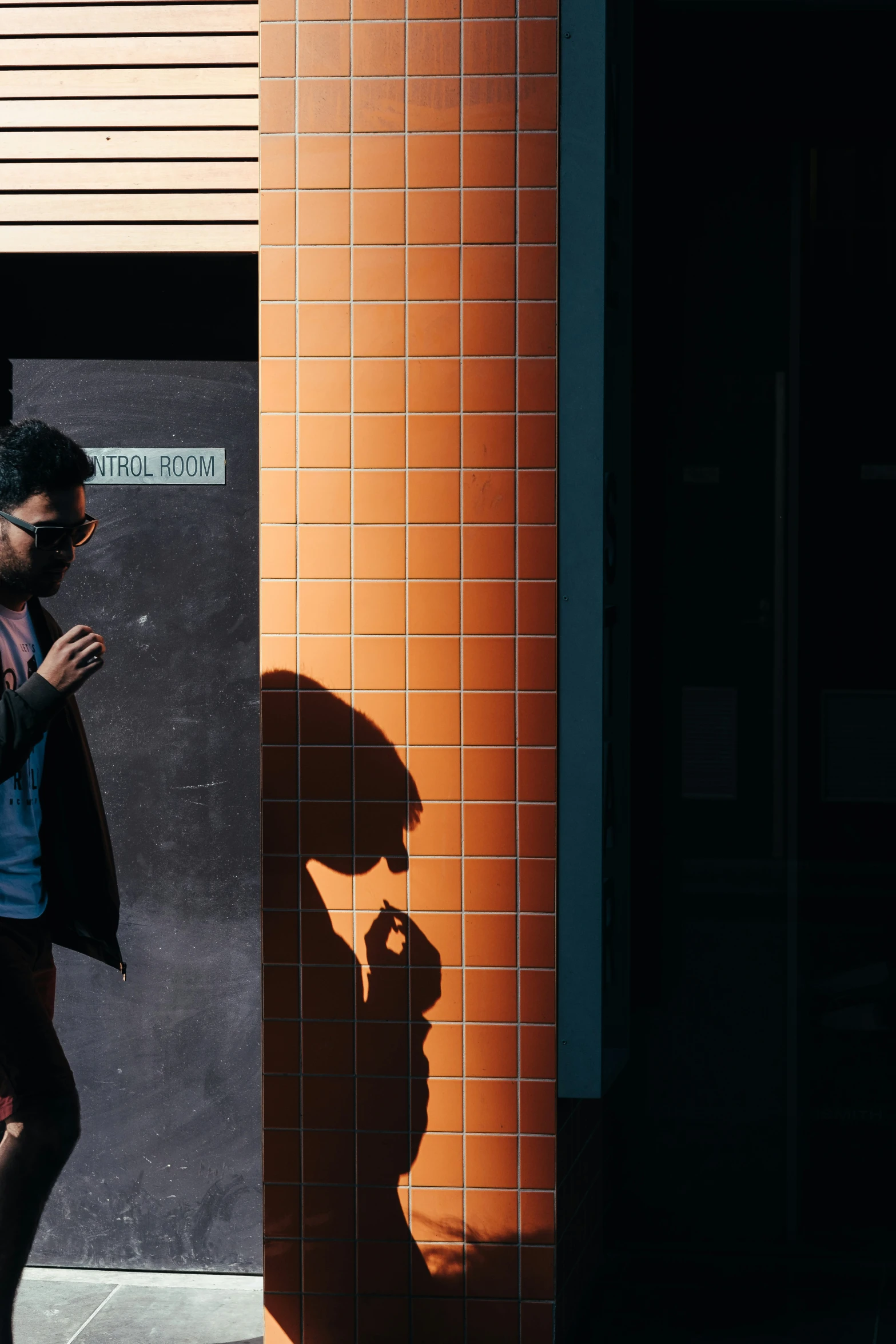 a young man with a cellphone walks by a building