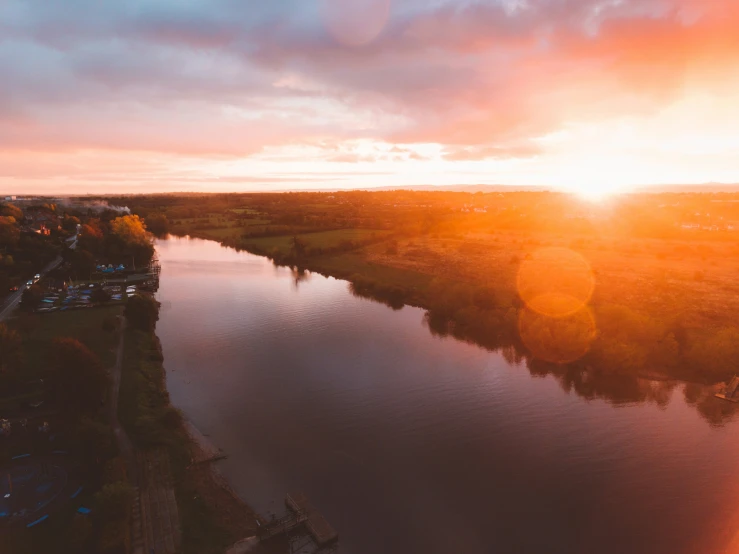 the sun is setting on the river bank