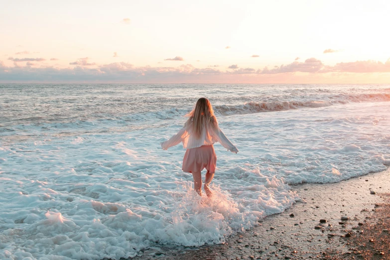 a woman on the shore with a surfboard is running into the waves