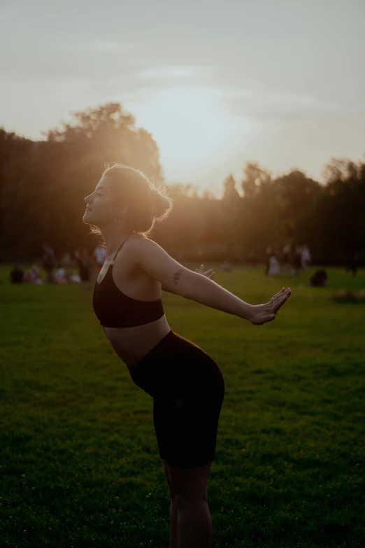 woman posing with her arms spread open in a park