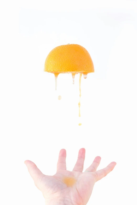 a person holding out their hand to a orange with a drop of water on top