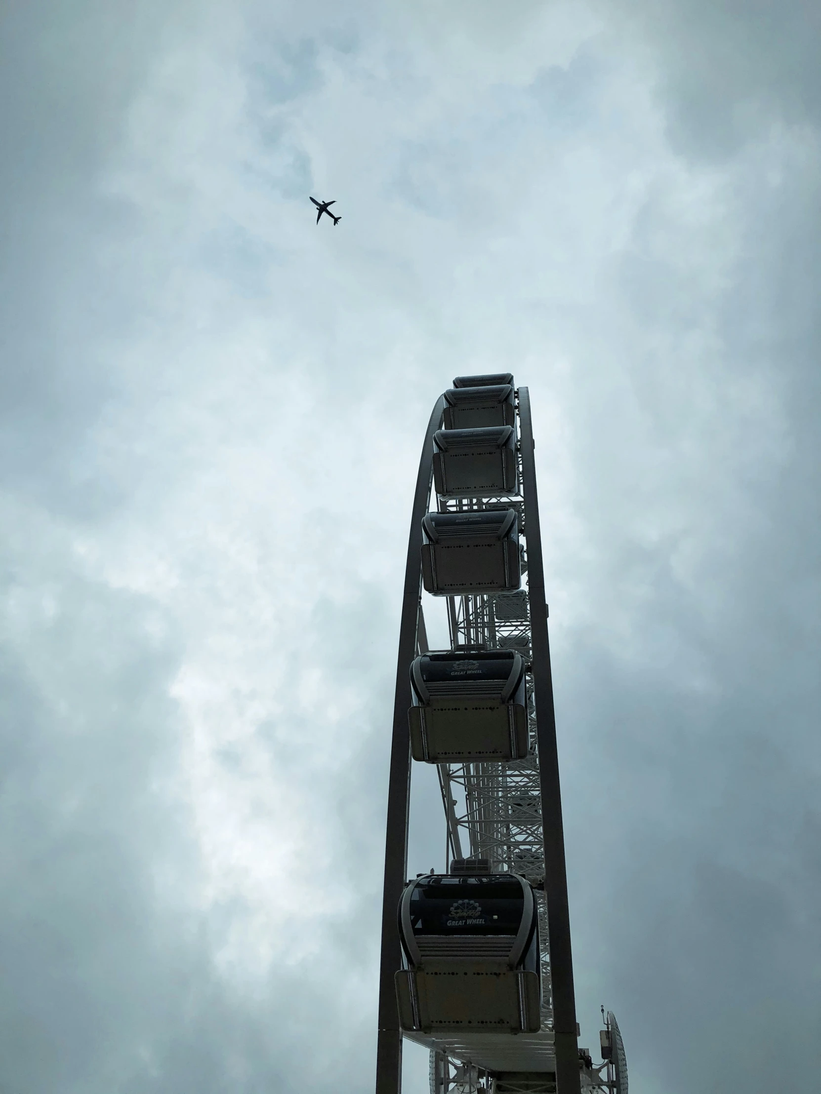 an airplane flying over the ocean near a ferris wheel