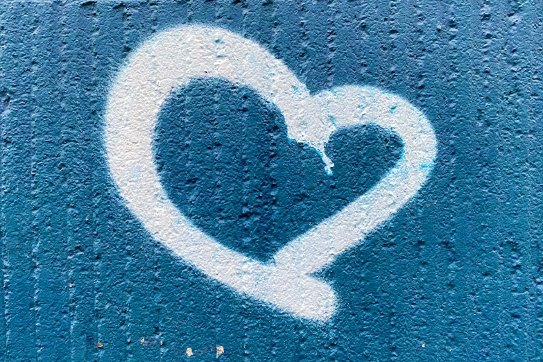 white heart on the blue concrete surface with word love painted above it