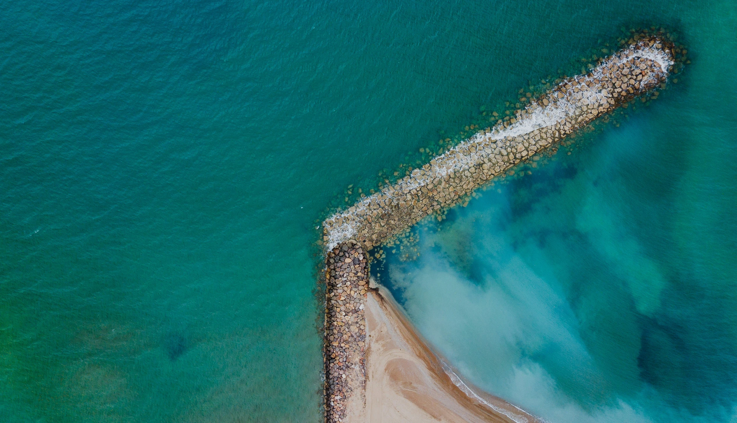 an aerial view of the water and sandy shore