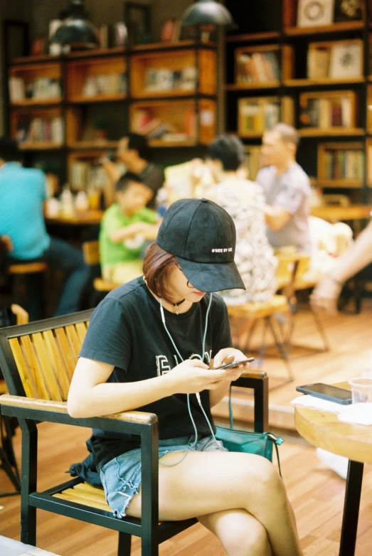 a girl sits on a chair and looks at her cellphone