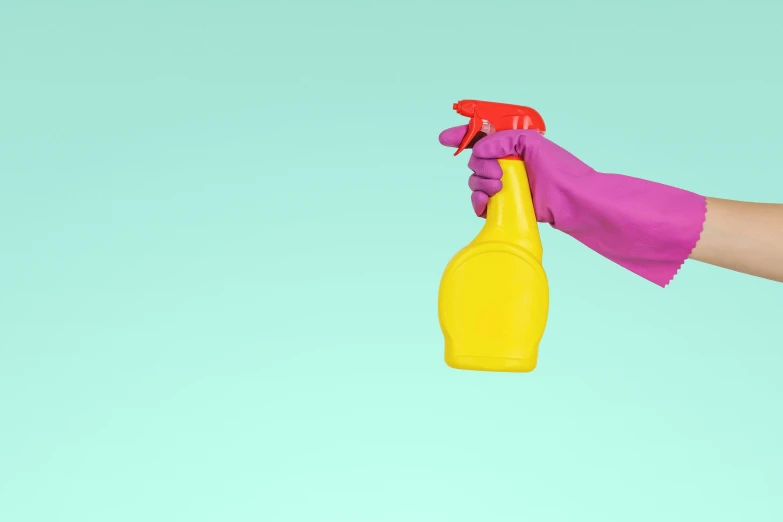 a person with purple gloves holding a yellow bottle with pink foam and red rubber gloves