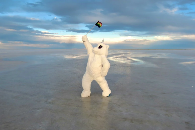 a man in white bodysuit flying a kite on the beach