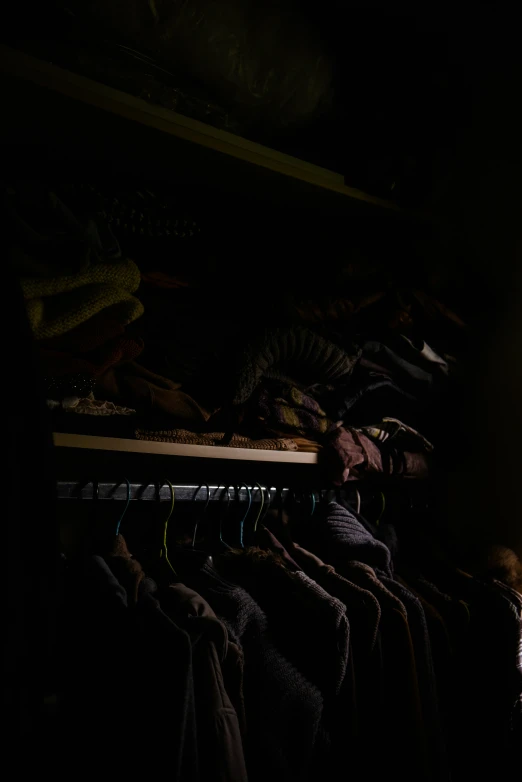 a rack of shirts hanging in a dark room