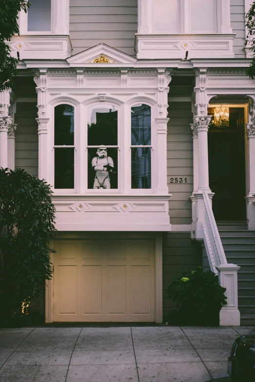 two story house with windows and an animal statue in the bay window