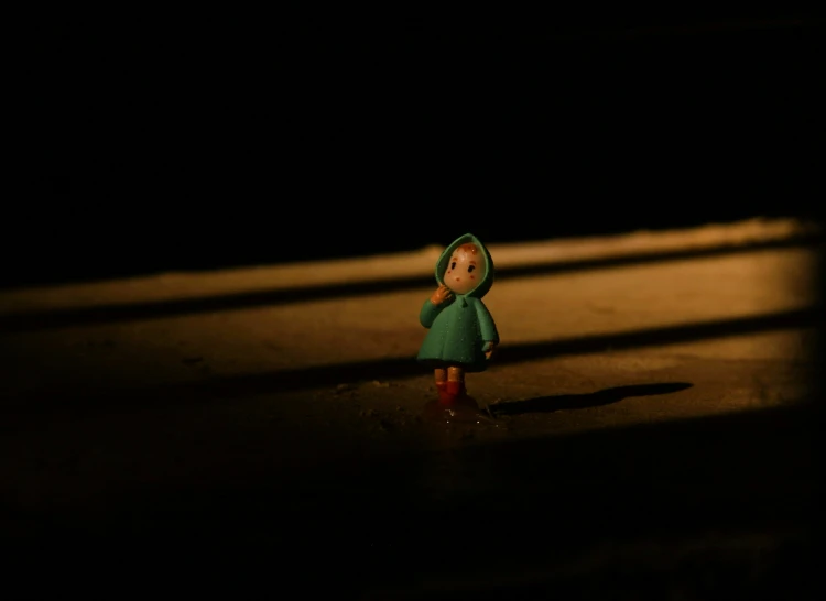 small doll doll next to light on pavement at night