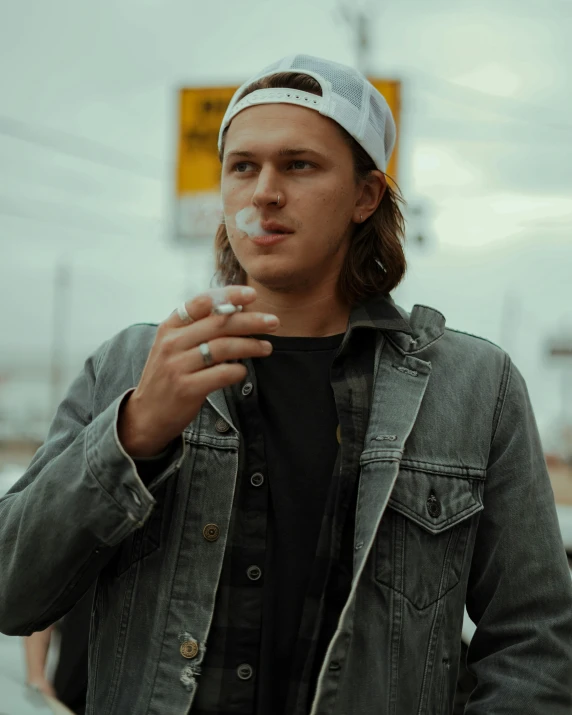 a young man with long hair smoking a cigarette