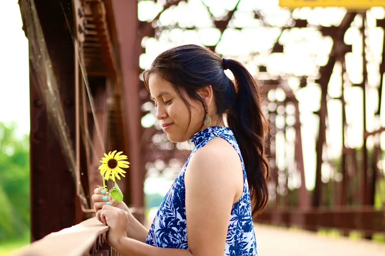 a woman is holding a flower and looking down at it