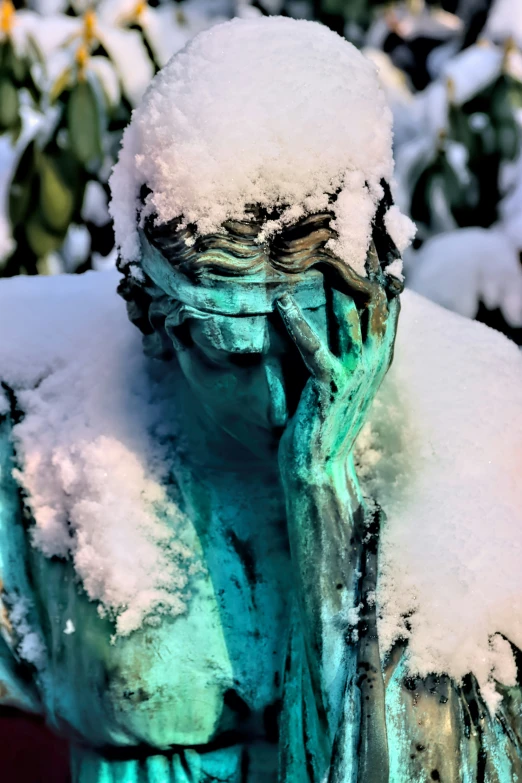 a statue sitting in the snow covered forest