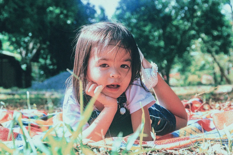 a girl in the grass with her face in her hands