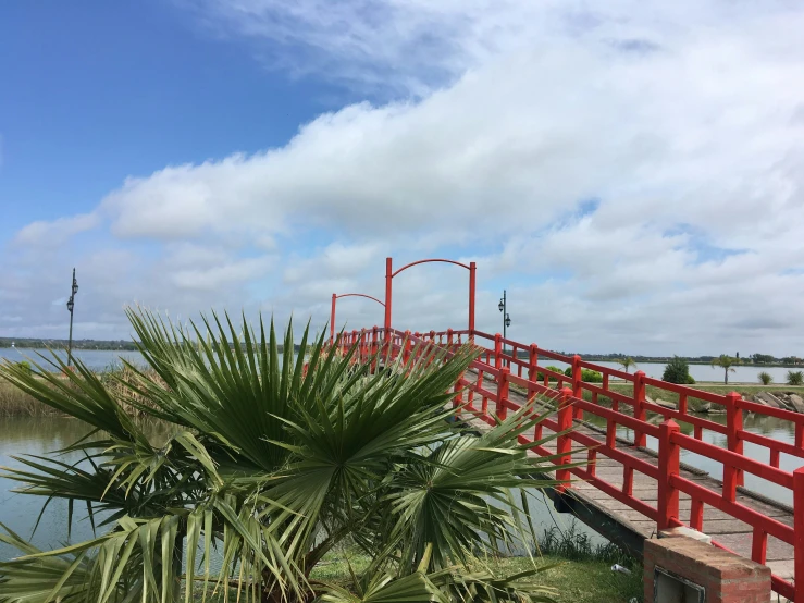 a long red bridge next to a lake