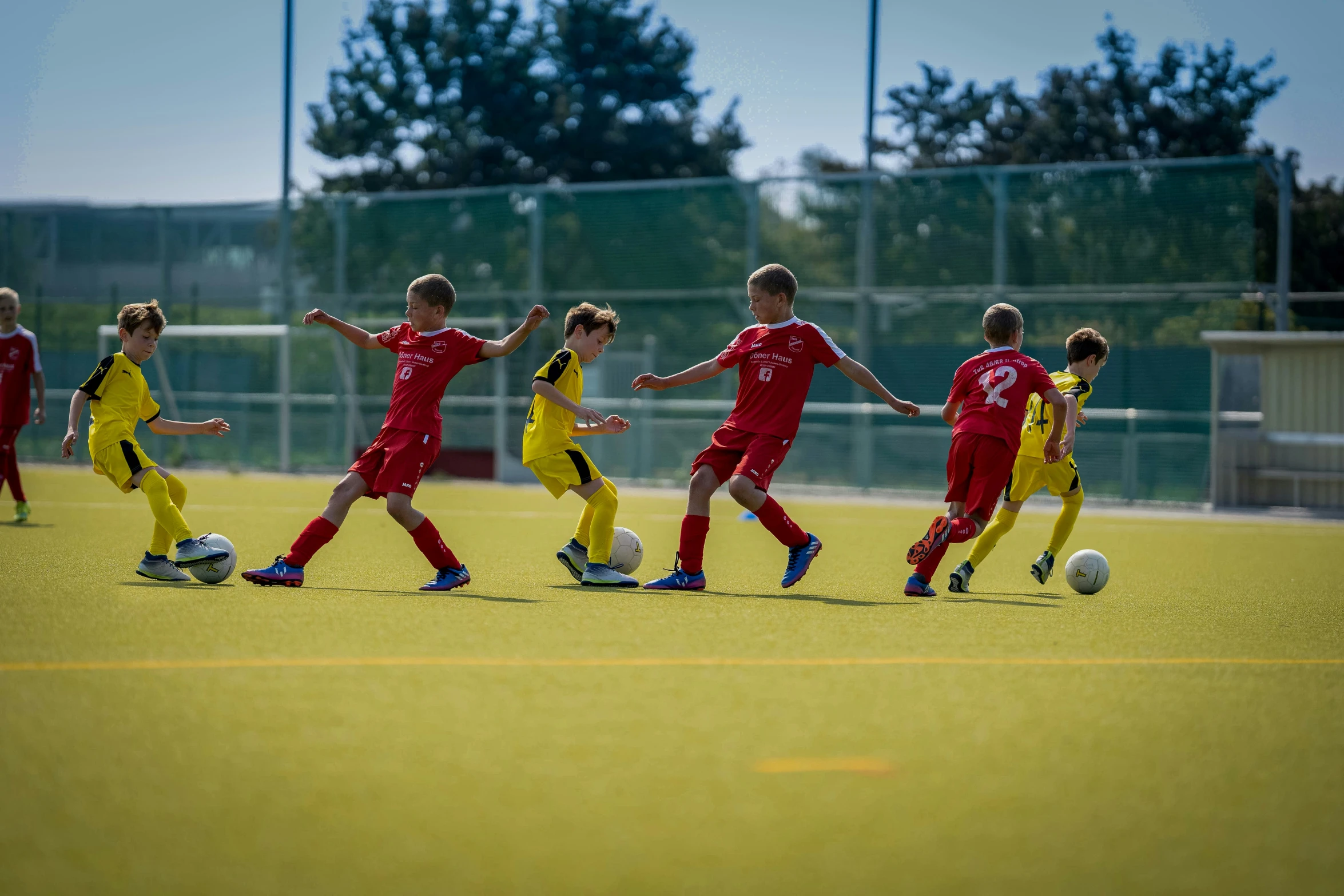 young soccer players in uniforms practicing on a soccer field