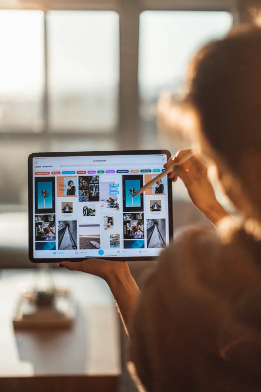 woman holding up an ipad with pictures of a living room on the screen