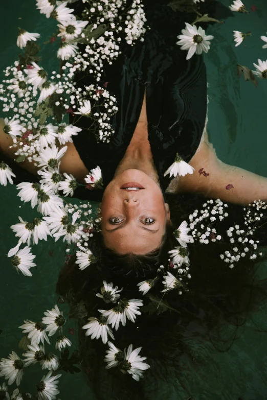 a girl floating in water with daisies around her