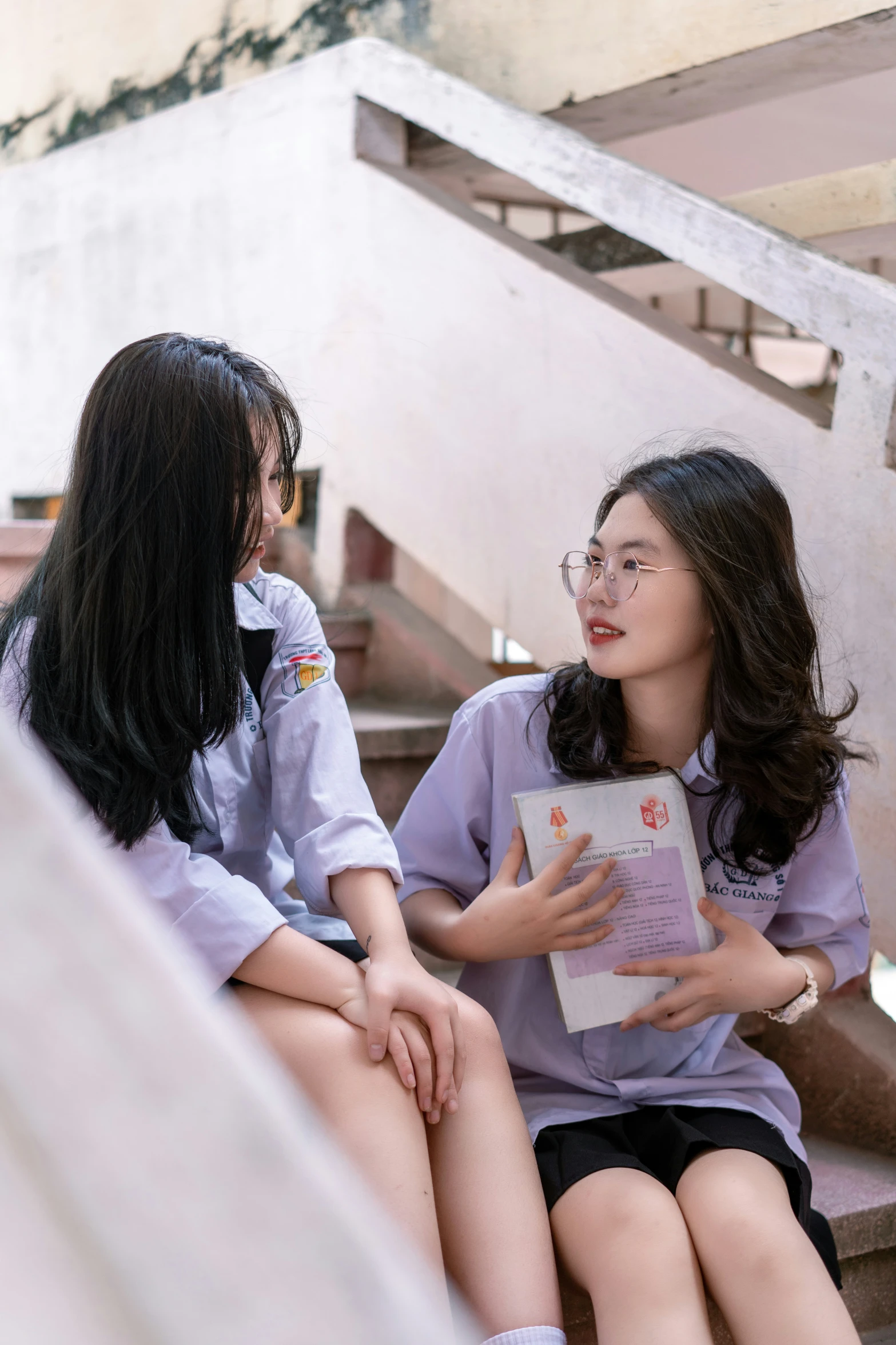 two girls wearing school uniforms are sitting down