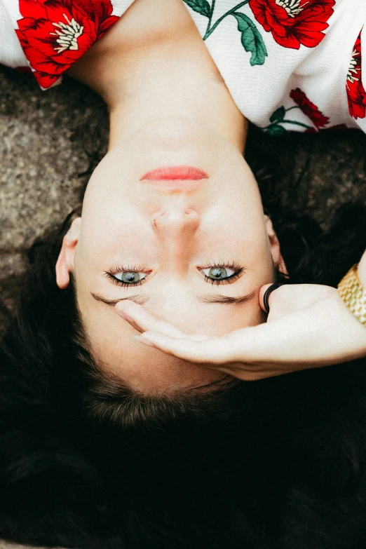 a woman with blue eyes lying down and making a heart