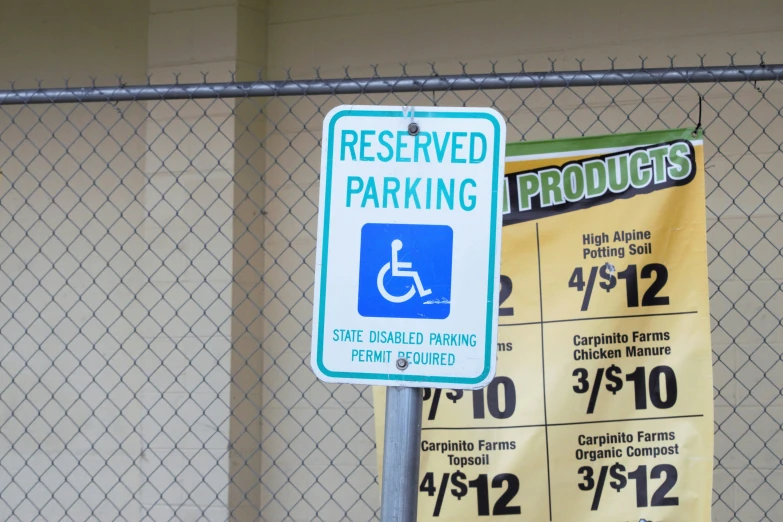 a green sign attached to a fence next to some parking information