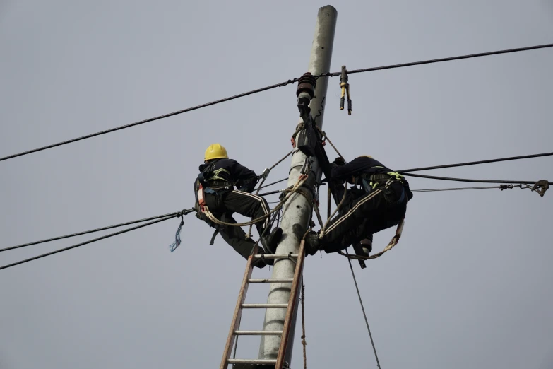 there are some people climbing a tall power pole