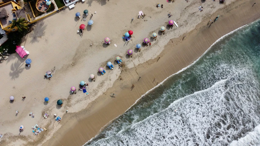 an aerial view of people on a beach and umbrellas